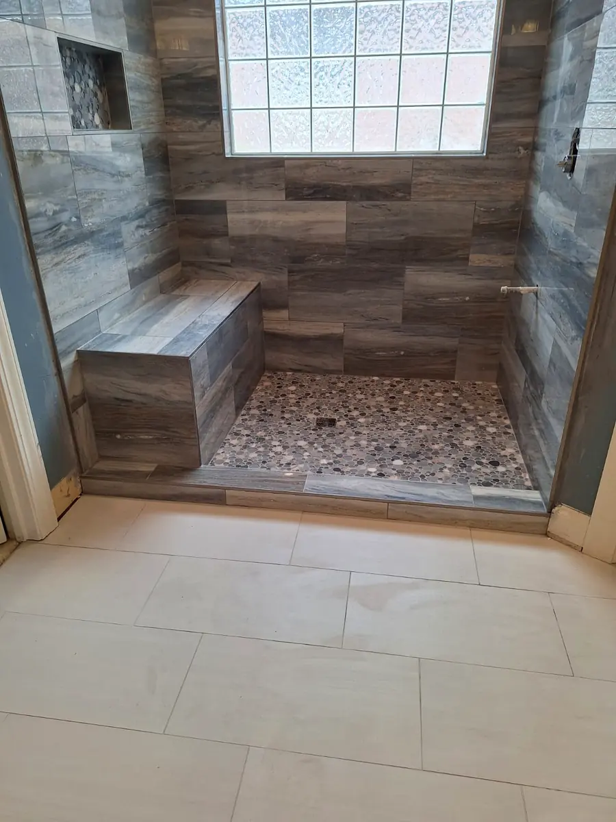 Finished walk-in shower with tiled bench, pebble floor and large-format floor tile